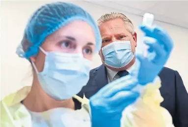  ?? NATHAN DENETTE THE CANADIAN PRESS FILE PHOTO ?? Premier Doug Ford watches a worker prepare a dose of the Pfizer-BioNTech COVID-19 vaccine on Jan. 7. “What, exactly, do the federal Opposition party and provincial government think they would have done better?” asks reader Patricia Orr.