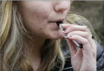  ?? STEVEN SENNE — THE ASSOCIATED PRESS ?? In this Wednesday photo, an unidentifi­ed 15-year-old high school student uses a vaping device near the school’s campus in Cambridge, Mass. Health and education officials across the country are raising alarms over wide underage use of e-cigarettes and...