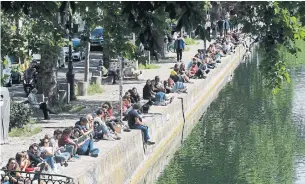  ?? FRANCOIS GUILLOT AFP/GETTY IMAGES ?? People sit on a bank of the Canal Saint-Martin in Paris on Saturday, on the first weekend after France eased lockdown measures taken to curb the spread of the COVID-19 pandemic.