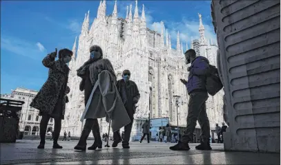  ?? Luca Bruno The Associated Press ?? People wear masks to curb the spread of COVID-19 as they walk Friday next to the Duomo cathedral, in Milan, Italy.