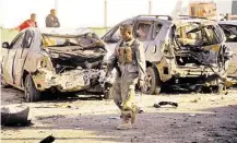  ?? Mohamed Abdiwahab / AFP / Getty Images ?? A Somali soldier walks past cars in front of Liido Seafood Restaurant. Militants detonated a bomb before storming in.