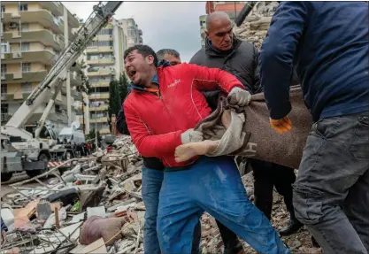  ?? CAN EROK — AFP VIA GETTY IMAGES ?? A rescuer reacts as he carries a body found in the rubble in Adana, Turkey, on Monday, after a magnitude 7.8earthquak­e struck the country's southeast. The combined death toll has risen to more than 3,400for Turkey and Syria after the region's strongest quake in nearly a century.