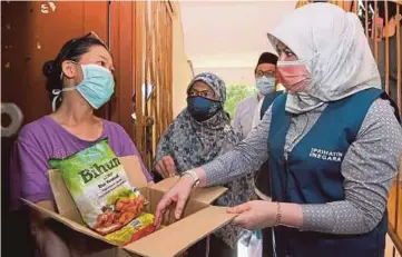  ?? BERNAMA PIC ?? Women, Family and Community Developmen­t Minister Datuk Seri Rina Mohd Harun handing a food basket to Low Pui Fun at Wangsa Maju in Kuala Lumpur yesterday.