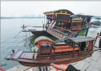  ?? PHOTOS BY XU YU / XINHUA ?? Right: Han stands beside the red boat with a self-made
red boat model in hand on the banks of Nanhu Lake in Jiaxing.