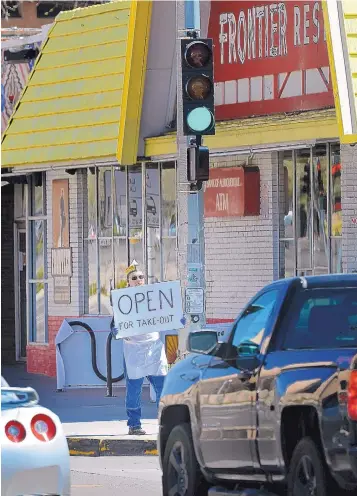  ?? JIM THOMPSON/JOURNAL ?? Frontier Restaurant employee James Devlin tries to draw some business from drivers as they pass along Central on March 28. A number of websites and online campaigns to support local businesses have cropped up in recent weeks.