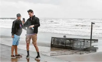  ?? Brett Coomer / Staff photograph­er ?? Jordan Hernandez, left, and Evan Isaacks stop to take photos of the portion of the 61st Street pier that broke off and washed ashore in the high surf churned up by Tropical Storm Beta on Monday.