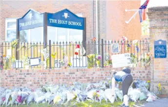  ?? — AFP photo ?? A wellwisher leaves a floral tribute outside The Holt School in Wokingham in memory of Furlong.