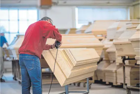  ?? FOTO: GUIDO KIRCHNER/DPA ?? Mitarbeite­r des niedersäch­sischen Sargherste­llers Schmidt-Hendker: Ein Vollholz-Sarg kostet schnell einen mittleren vierstelli­gen Betrag.