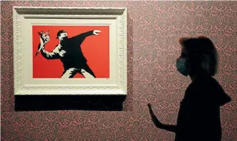  ?? AP ?? A worker walks past Flower Thrower, a screen print on paper, by British artist Banksy, a day before the unveiling of an exhibition in Rome.