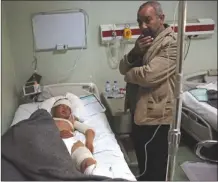  ?? The Associated Press ?? Nazim Hamid stands next to his injured son Yasir, 11, in a hospital in Irbil, Iraq, on Saturday. The boy is a victim of a possible IS chemical attack.