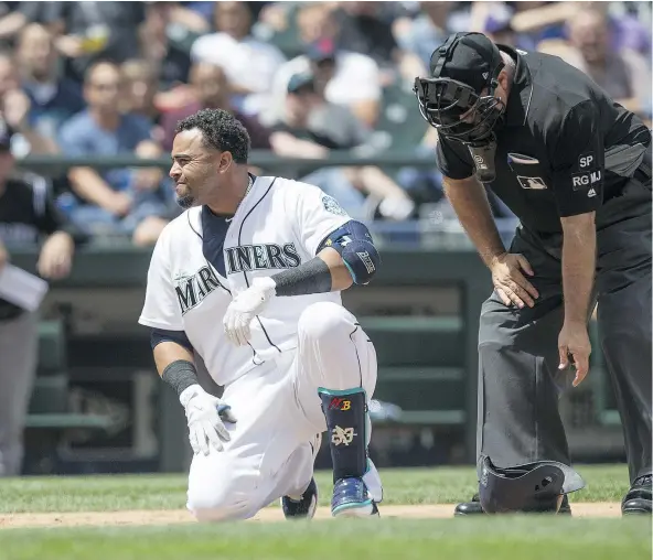  ?? — PHOTOS: GETTY IMAGES ?? Nelson Cruz of the Mariners reacts after being hit by a pitch thrown by starter Kyle Freeland of the Rockies during the third inning of a game at Safeco Field on Thursday in Seattle, Wash. At right is home plate umpire Brian O’Nora.