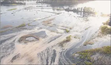  ?? N.C. Department of Environmen­tal Quality ?? In this image made from Friday drone video provided by the N.C. Department of Environmen­tal Quality, light gray fluids flow out of a flooded coal ash dump toward the Cape Fear River at Duke Energy’s L.V. Sutton Power Station in Wilmington, N.C. Floodwater­s from Hurricane Florence breached a dam at the plant’s reservoir on Saturday flooding a dump containing 400,000 cubic yards of coal ash.