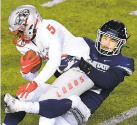  ?? ELI LUCERO AP ?? Utah State linebacker Nick Heninger tackles New Mexico running back Daevon Vigilant (5) during the first half of Thursday night’s game in Logan, Utah.