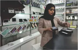  ?? VAHID SALEMI/AP ?? A cellphone vendor works at her shop in Tehran. The government last year banned the use of iPhone 14 and 15, meaning the iPhone 13 is the “newest” available.