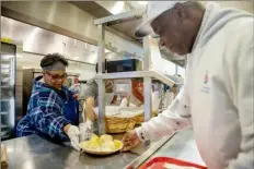  ?? ?? Mattie Hardine, of East Liberty and a member of the Urban League of Greater Pittsburgh, serves Leon Cargile, of Forest Hills, a Thanksgivi­ng meal at the East End Cooperativ­e Ministry in East Liberty on Friday.