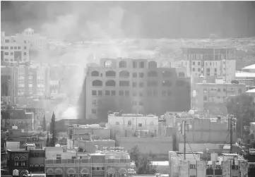  ??  ?? Smoke billows behind a building in Sanaa, during clashes between Huthi rebels and supporters of Saleh. — AFP photo