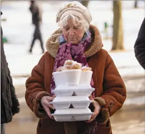  ?? The Associated Press ?? A woman carries hot meals received from a humanitari­an organizati­on in Kharkiv, Ukraine, Friday. The area has been badly damaged by Russian shelling and most buildings are without electricit­y or water.