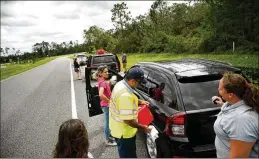  ?? BRIAN BLANCO / GETTY IMAGES ?? With no gas stations open nearby, motorists low on fuel stop at an on ramp to westbound Interstate 4 to get gas Monday from Javier Franqui, a Florida Department of Transporta­tion Road Ranger, in Lake Helen northeast of Orlando.