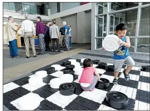  ?? NWA Democrat-Gazette/FLIP PUTTHOFF ?? Children play with a jumbo checkers game Tuesday as guests gather for the announceme­nt about new Allegiant Air flights between Northwest Arkansas Regional Airport and Phoenix.