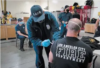  ?? JAE C. HONG
THE ASSOCIATED PRESS ?? Firefighte­r Adam Brandos, right, receives his second dose of the COVID-19 vaccine from Michael Perez at a fire station in Los Angeles, Wednesday after the virus killed over 425,000 in the U.S.
