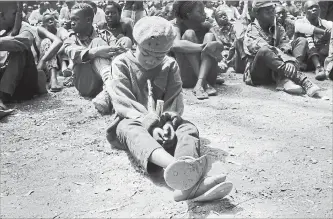  ?? SAM MEDNICK THE ASSOCIATED PRESS ?? A young child soldier sits on the ground at a release ceremony in February when he and others laid down their weapons and traded in their uniforms to return to “normal life,” in Yambio, South Sudan.