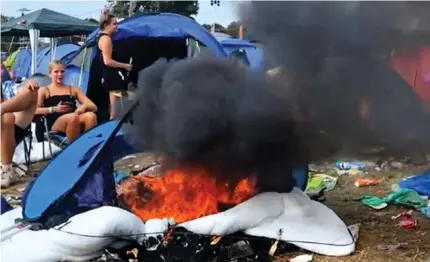  ?? ?? Ablaze: Festival-goers watch as smoke rises from a burning tent in the campsite at Reading Festival