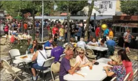  ?? EVAN BRANDT — DIGITAL FIRST MEDIA ?? Although a bit on the warm side, the weather was perfect for the 13th Annual Carousel of Flavor. Here, diners enjoy their choices in Smith Family Plaza.