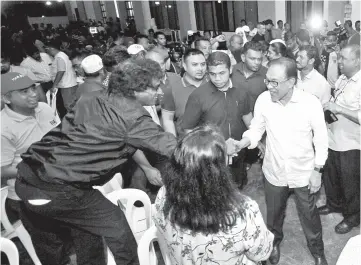  ??  ?? Anwar Ibrahim (right) shaking hands with the by-election machinery during a meeting at Rantau Exco Park yesterday. - Bernama photo