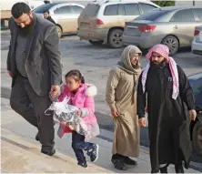  ?? Members of Hayat Tahrir Al-Sham alliance escort four-year-old girl named Yasmine near the Bab Al-Hawa crossing with Turkey on Tuesday. ??