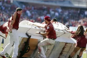  ?? Associated Press See Short Snaps, this page. ?? A stadium crew works to right the Oklahoma Sooner Schooner Saturday after it rolled over on the field in the middle of a first-half touchdown celebratio­n.