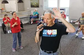  ?? MORNING NEWS/TNS REBECCA SLEZAK/DALLAS ?? Susan Norris dances as Eric Kolb, a founder of the nonprofit Songs & Smiles, spins while singing with residents on June 14 at Villagio of Carrollton in Carrollton, Texas. Those in attendance danced and sang along to popular 1960s-era songs. Kolb has visited the residents to sing twice a month over the last year.