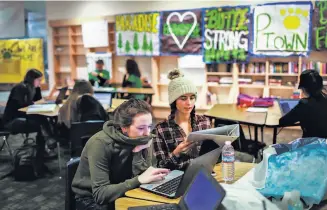  ??  ?? Faith (left) works on her college essays alongside friend Kaylee Suniga at a makeshift classroom in the Chico Mall set up to temporaril­y serve Paradise high school students.