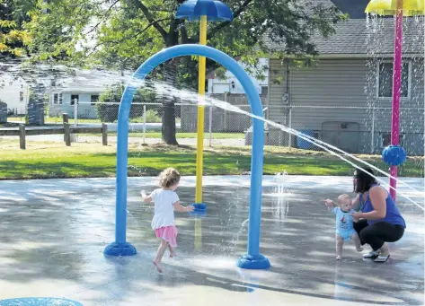  ?? PHOTOS BY ALLAN BENNER/STANDARD STAFF ?? Addison Scapillati, with her brother Nash and mother Sharau, was among the first children to enjoy the new splashpad at West Park Friday.