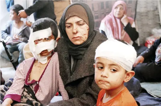  ??  ?? Syrians, who were injured in a suicide car bombing that targeted buses carrying evacuees, sit in a tent on the Syrian-Turkish border in Idlib Monday. (AFP)