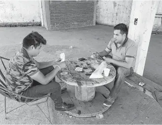  ?? Alfredo Corchado / Dallas Morning News ?? Gustavo Cortez plays cards with his cousin Cesar Cortez as they began their shift to help protect Aguacate Sur, Mexico. Much of the funding for their security force comes from avocado growers.
