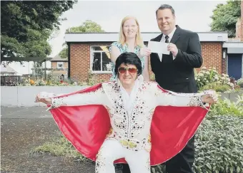  ??  ?? Funeral director and Elvis impersonat­or Fred Davies donates a cheque worth £1,000 to Alzheimer’s Society staff.