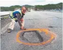  ?? DAVID BOYD/THE CANADIAN PRESS ?? Ernest Barnes, 70, paints orange circles around a highway’s notorious potholes.