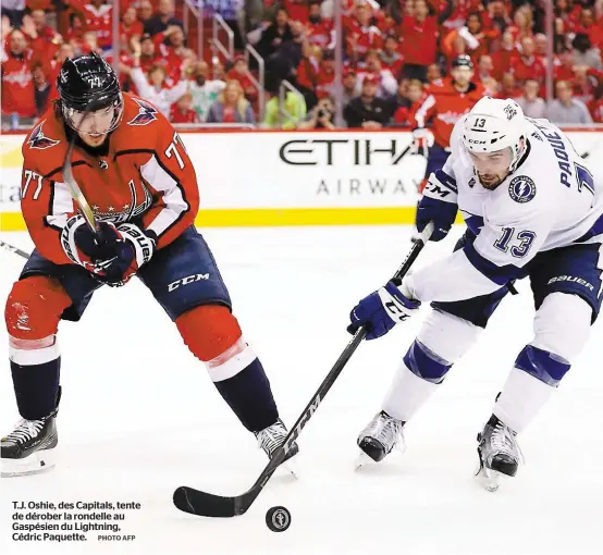  ?? PHOTO AFP ?? T.J. Oshie, des Capitals, tente de dérober la rondelle au Gaspésien du Lightning, Cédric Paquette.