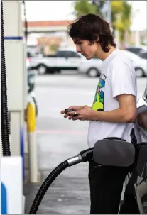  ?? Eddy Marquez/The Signal ?? Cristian Ganges puts gas in his car on Monday. Residents have now collected more than 900,000 signatures to put a gas tax repeal initiative on the November ballot.