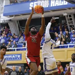  ?? RICH SCHULTZ — GETTY IMAGES ?? Saint Joseph’s Christ Essandoko, center, goes up for a shot over Seton Hall’s Kadary Richmond, right, during the second half of a first-round NIT game at Walsh Gym on Wednesday in South Orange, New Jersey. Seton Hall won the game, 75-72, in overtime.