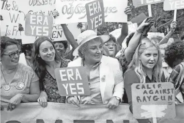  ?? AP ?? Bella Abzug, center, smiles as she holds up her Equal Rights Amendment sign in a demonstrat­ion in New York City on Aug. 26, 1980. Abzug, in 1974, introduced the Equality Act in the House of Representa­tives.