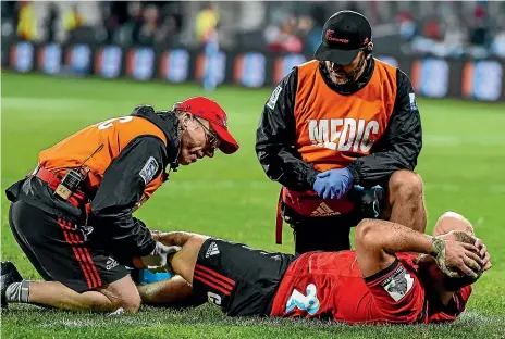  ??  ?? Crusaders loosehead prop has his injured leg assessed by physiother­apist John Roche, left, and doctor Martin Swan.