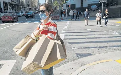  ?? /Bloomberg ?? Business not as usual: A pedestrian wearing a protective face mask carries shopping bags in San Francisco, California, last week.