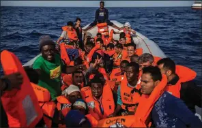 ?? AP/OLMO CALVO ?? Migrants aboard a rubber dinghy off the Libyan coast receive life vests from rescuers aboard the Open Arms aid boat Saturday.