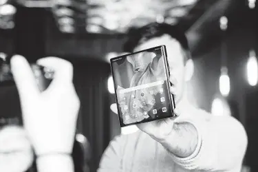  ?? Chris Ratcliffe / Bloomberg ?? An attendee at a London launch event on Tuesday holds a Mate Xs folding smartphone, manufactur­ed by Huawei Technologi­es Co. It’s the company’s first folding phone to be available internatio­nally.