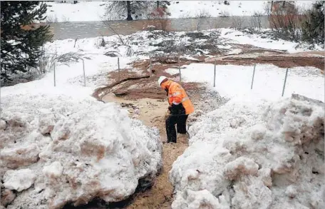  ?? Gary Coronado Los Angeles Times ?? CALTRANS WORKER Christian Ochoa, 28, removes debris to allow water to f low into the Truckee River, which topped its banks Sunday, submerging picnic tables on campground­s along Highway 89 north of Lake Tahoe. Forecaster­s said it could rise an...