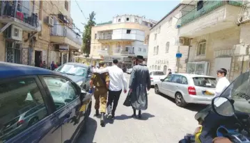  ?? (Courtesy) ?? A TOLDOT AHARON hassid (right) and another haredi man escort the author’s son from an anti-Zionist mob in the capital’s Mea She’arim neighborho­od last Friday.