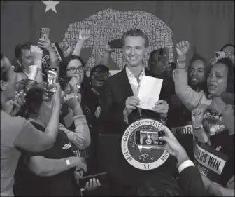  ?? Alisha Jucevic/ Calmatters ?? Gov. Gavin Newsom (D) stands with cheering fast food workers after signing legislatio­n raising their minimum wage in Los Angeles on Sept. 28.