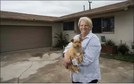  ?? PAUL BERSEBACH — STAFF PHOTOGRAPH­ER ?? Debbie Marcusson holds her dog, Baron, in front of a house she rents in Huntington Beach. She began house-hunting two years ago with no success.