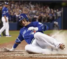  ?? FRANK GUNN/THE CANADIAN PRESS ?? After getting a good read on Ezequiel Carrera’s soft single in the fourth, Troy Tulowitzki slides home with the Jays’ second run in Game 4.